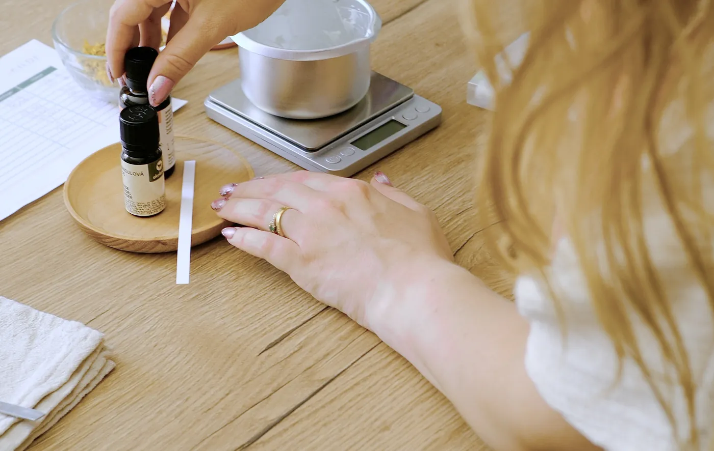 Une participante saisit une fiole d’huile essentielle, la balance et la fiche de pesée devant elle